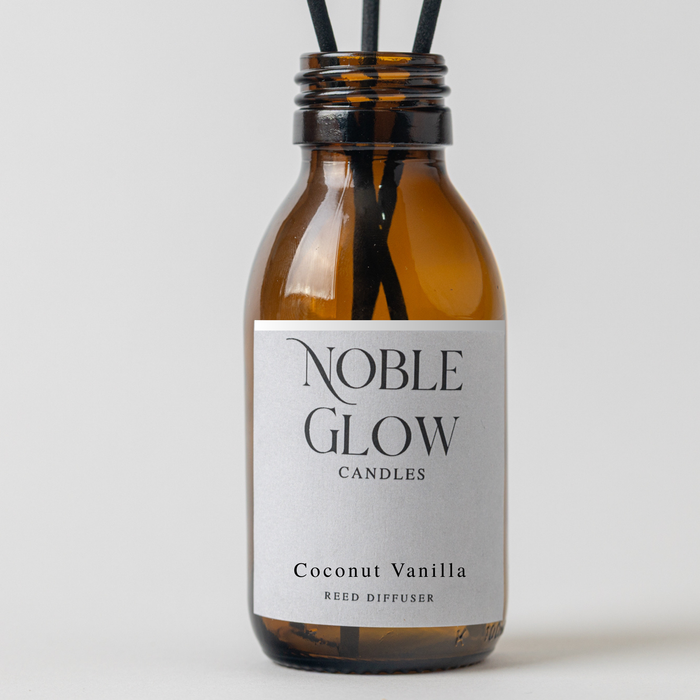 Reed diffuser labeled 'Noble Glow Candles' with coconut vanilla scent on a light gray background