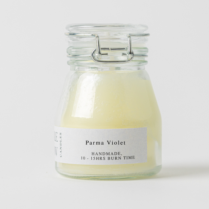 Glass jar candle labeled 'Parma Violet' on a white background