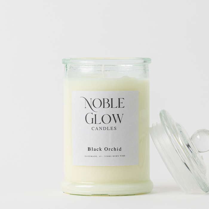 Candle in a glass jar labeled 'Noble Glow Candles Black Orchid' on a white background