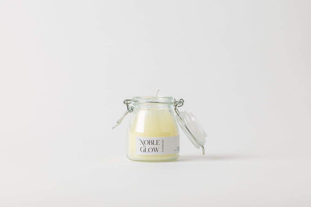 Jar of candle labeled 'Noble Glow' on a white background